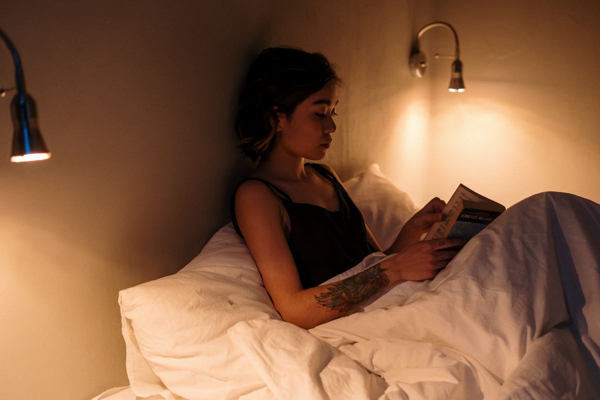 Woman reading in bed under a warm light